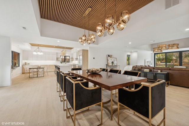 dining space with a tray ceiling and light wood-type flooring