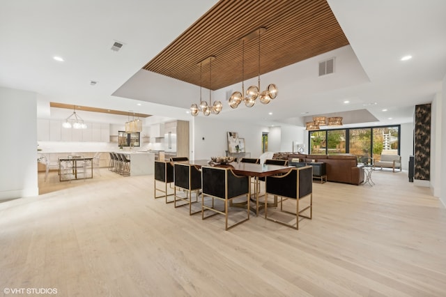 dining room featuring light wood-type flooring, a high ceiling, and a chandelier