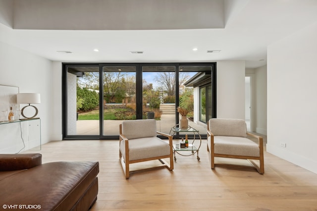 sitting room with light wood-type flooring and a wall of windows