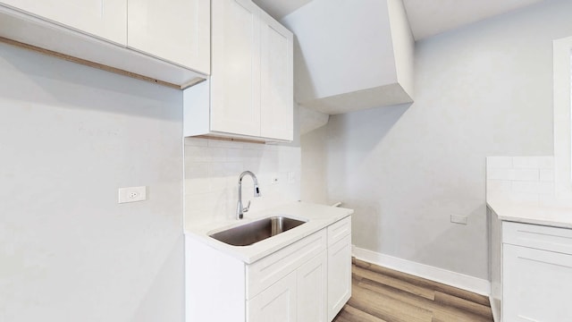 kitchen featuring backsplash, white cabinetry, sink, and light wood-type flooring