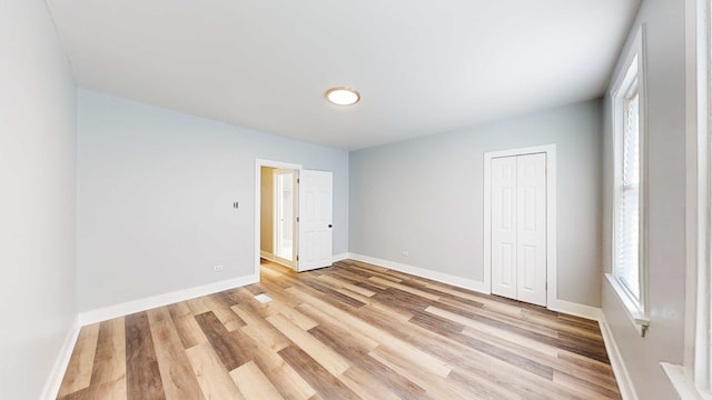 unfurnished bedroom featuring light wood-type flooring and a closet