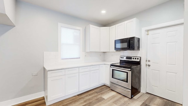 kitchen with stainless steel electric range, decorative backsplash, light hardwood / wood-style floors, and white cabinetry