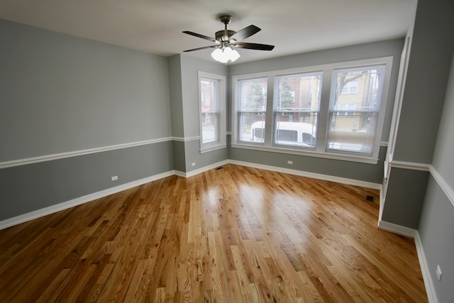 empty room featuring a wealth of natural light, ceiling fan, and light wood-type flooring