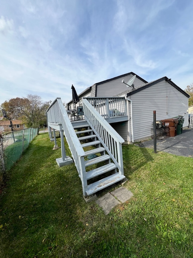 rear view of house featuring a lawn and a deck