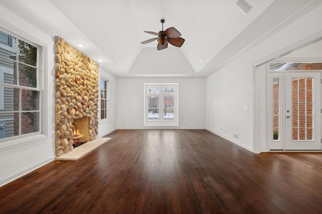 unfurnished living room featuring lofted ceiling, dark hardwood / wood-style flooring, a stone fireplace, a raised ceiling, and ceiling fan