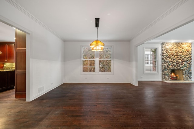 unfurnished dining area with dark wood-type flooring, a fireplace, and ornamental molding