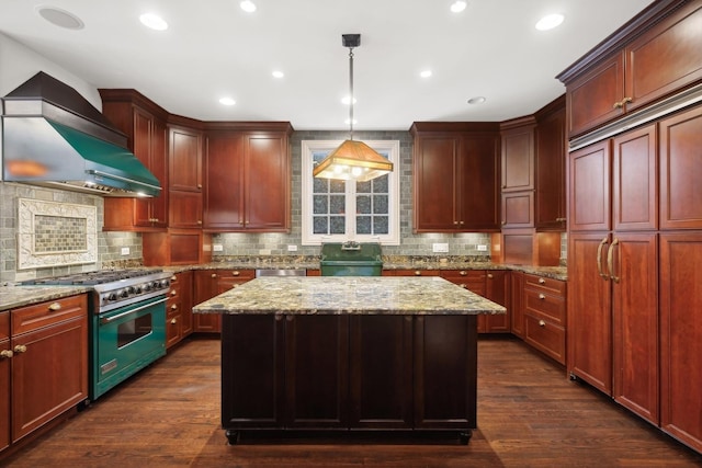 kitchen featuring appliances with stainless steel finishes, dark hardwood / wood-style flooring, hanging light fixtures, wall chimney exhaust hood, and a center island