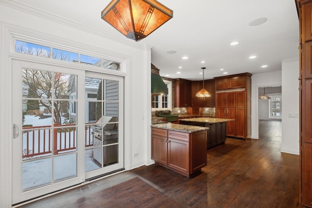 kitchen with pendant lighting, decorative backsplash, dark hardwood / wood-style floors, light stone counters, and crown molding