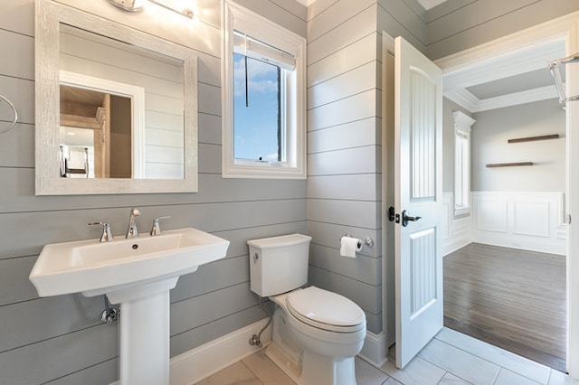 bathroom with hardwood / wood-style floors, wooden walls, toilet, and sink