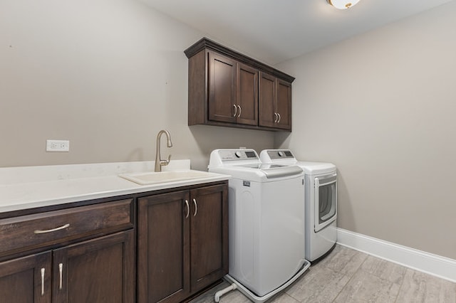 washroom with light wood-type flooring, cabinets, sink, and washing machine and clothes dryer