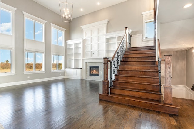 unfurnished living room featuring a towering ceiling and dark hardwood / wood-style floors