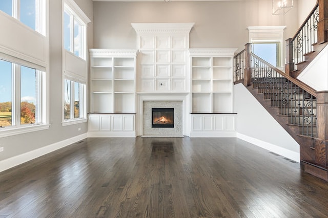 unfurnished living room featuring a wealth of natural light and dark hardwood / wood-style flooring