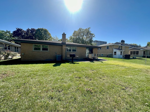 back of house featuring central AC unit and a lawn