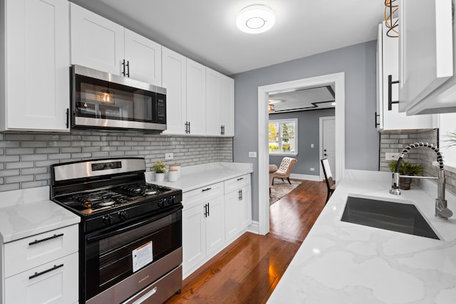 kitchen with white cabinets, appliances with stainless steel finishes, dark hardwood / wood-style flooring, and sink