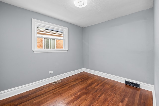 spare room featuring wood-type flooring and a textured ceiling