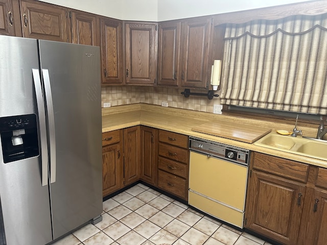 kitchen with decorative backsplash, sink, dishwashing machine, light tile patterned flooring, and stainless steel fridge