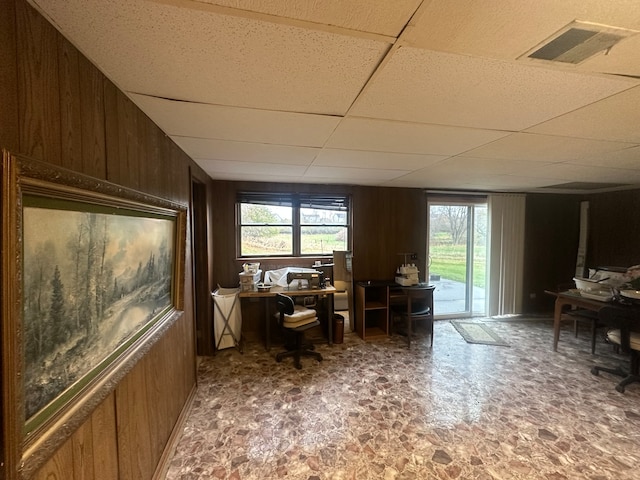 home office with wood walls and a paneled ceiling