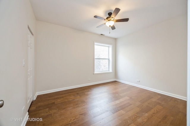 unfurnished room with a ceiling fan, dark wood-style flooring, visible vents, and baseboards