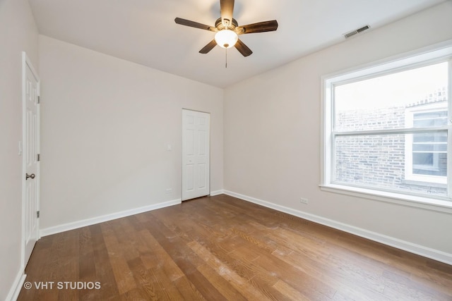 unfurnished room with visible vents, ceiling fan, baseboards, and wood finished floors