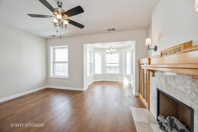 unfurnished living room featuring baseboards, visible vents, a premium fireplace, and wood finished floors