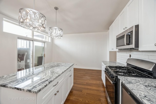 kitchen with range with gas cooktop, dark wood finished floors, stainless steel microwave, hanging light fixtures, and white cabinets