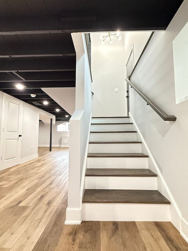 stairs featuring beam ceiling and hardwood / wood-style flooring