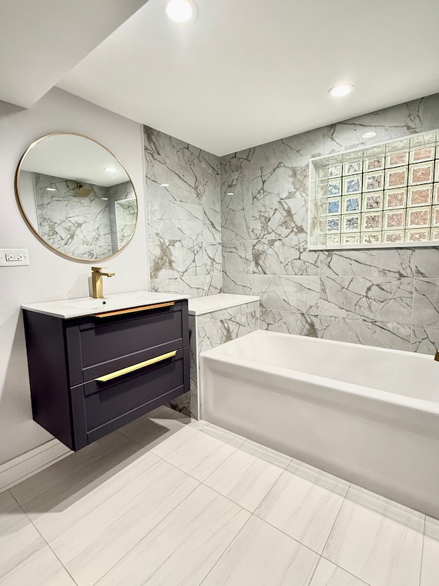 bathroom with a bathtub, vanity, and tile walls