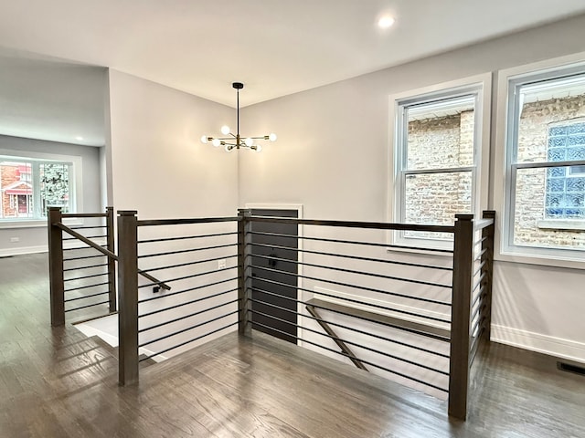 staircase with hardwood / wood-style floors and a chandelier