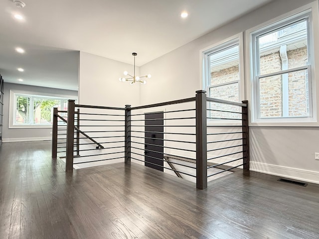 stairs featuring hardwood / wood-style floors and an inviting chandelier