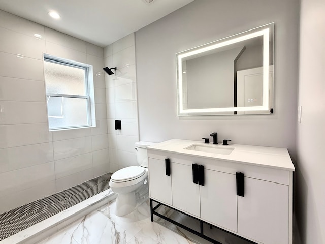 bathroom with tiled shower, vanity, and toilet