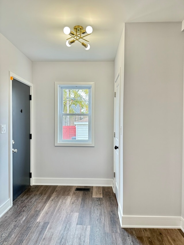 spare room with a chandelier and dark hardwood / wood-style floors