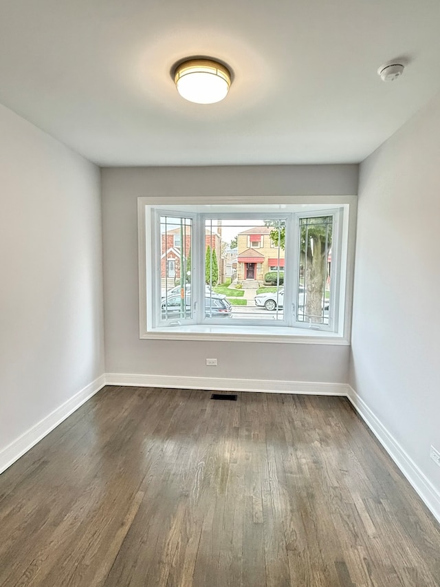 unfurnished room with dark hardwood / wood-style flooring and a healthy amount of sunlight