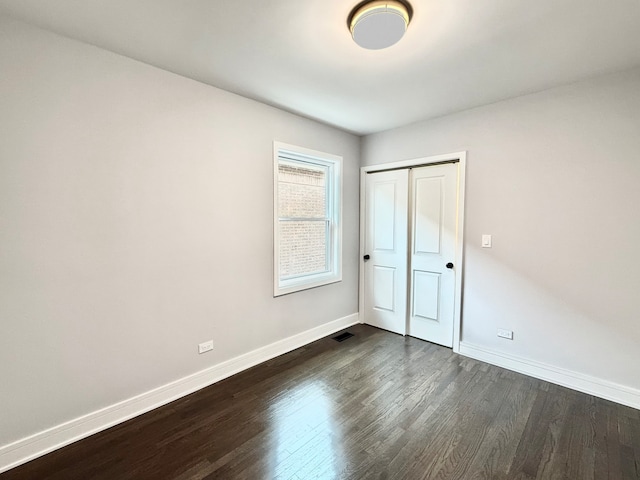 unfurnished bedroom with dark hardwood / wood-style floors and a closet