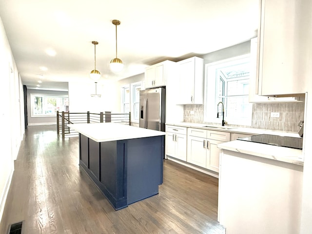 kitchen featuring sink, white cabinets, a kitchen island, stainless steel fridge with ice dispenser, and decorative light fixtures