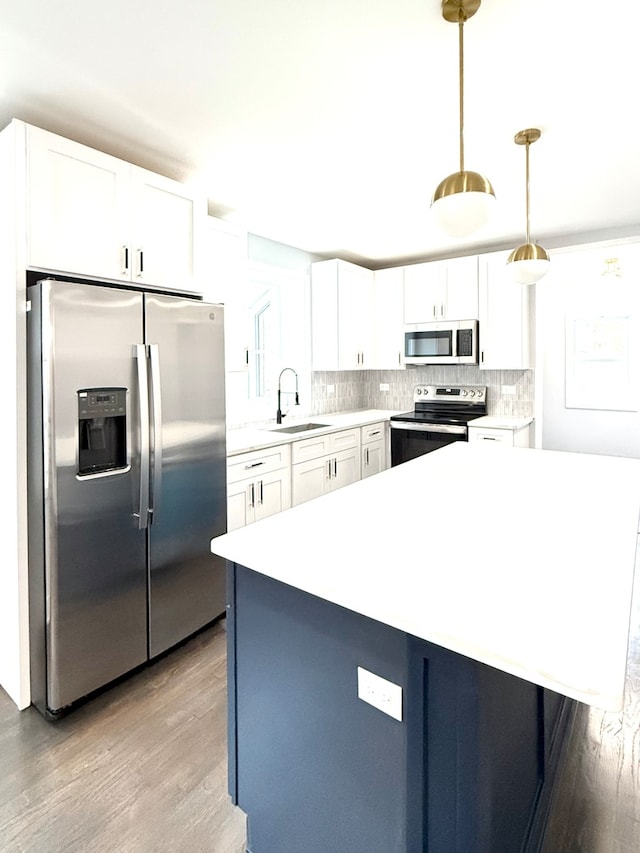 kitchen featuring sink, stainless steel appliances, light hardwood / wood-style floors, decorative light fixtures, and white cabinets