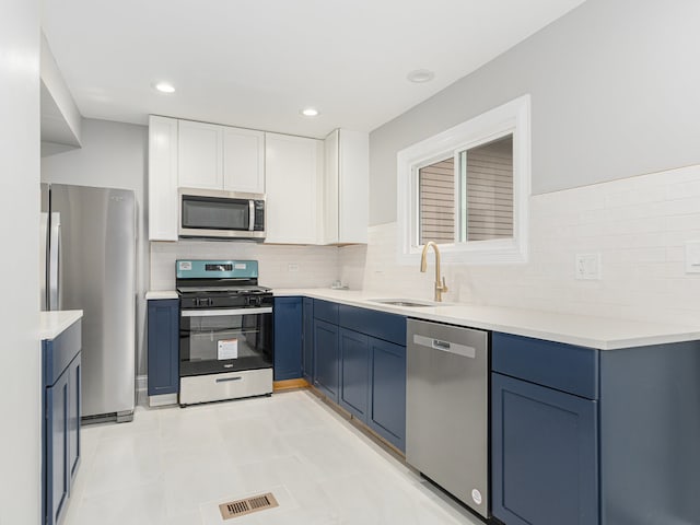 kitchen featuring stainless steel appliances, white cabinets, sink, tasteful backsplash, and blue cabinetry