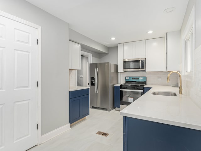 kitchen featuring white cabinetry, sink, appliances with stainless steel finishes, tasteful backsplash, and blue cabinets