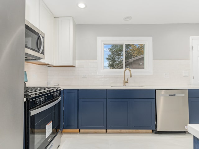 kitchen featuring stainless steel appliances, sink, tasteful backsplash, blue cabinets, and white cabinets