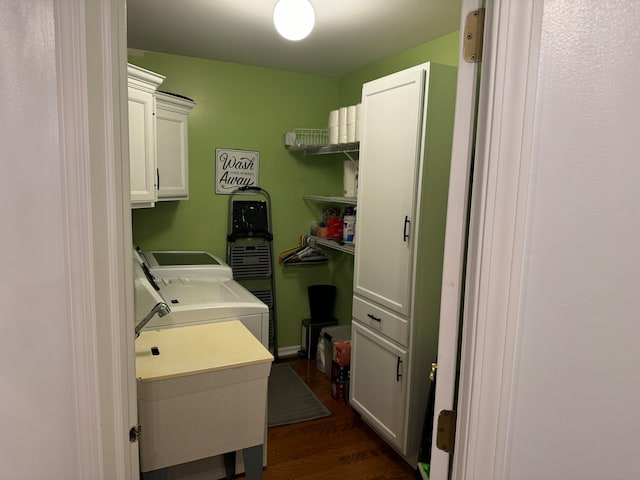 clothes washing area with dark hardwood / wood-style flooring, sink, cabinets, and independent washer and dryer