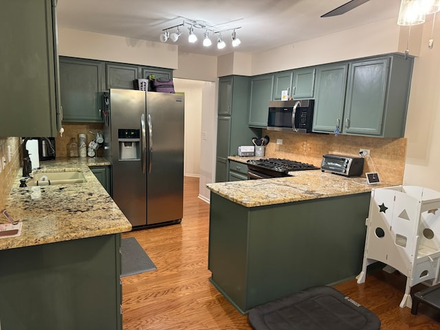 kitchen featuring kitchen peninsula, stainless steel appliances, decorative backsplash, and sink