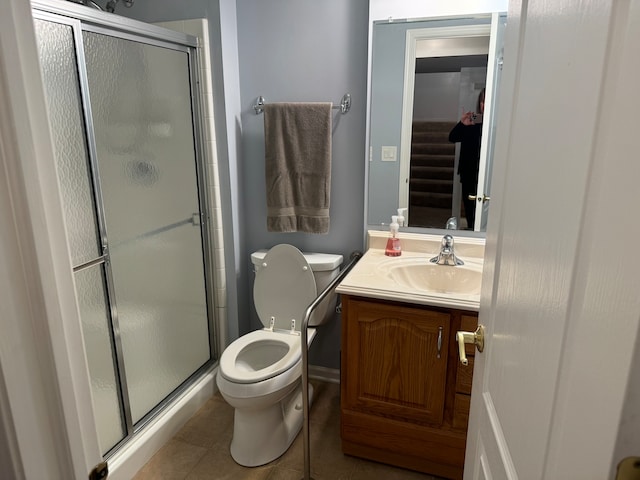 bathroom featuring toilet, vanity, tile patterned flooring, and a shower with shower door