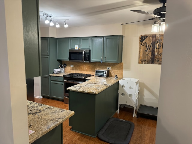 kitchen with stainless steel appliances, light stone countertops, backsplash, green cabinetry, and dark wood-type flooring