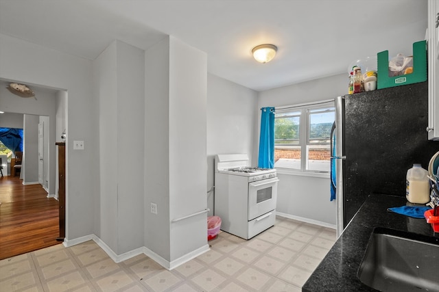 kitchen featuring white cabinets, white gas range, stainless steel refrigerator, and light hardwood / wood-style flooring