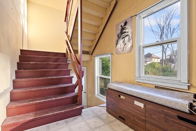 stairs with a wealth of natural light and vaulted ceiling