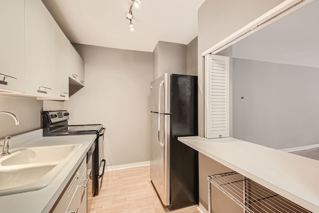 kitchen with white cabinets, appliances with stainless steel finishes, light hardwood / wood-style floors, and sink