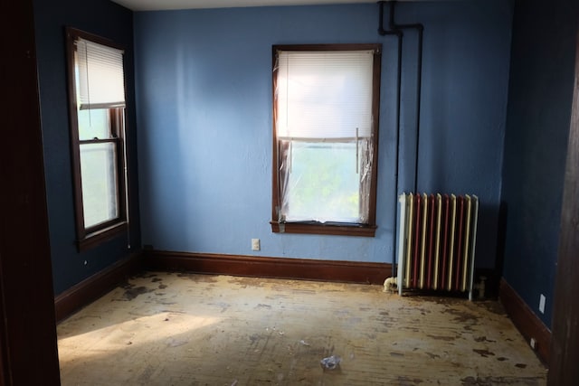 unfurnished room featuring radiator heating unit and a healthy amount of sunlight