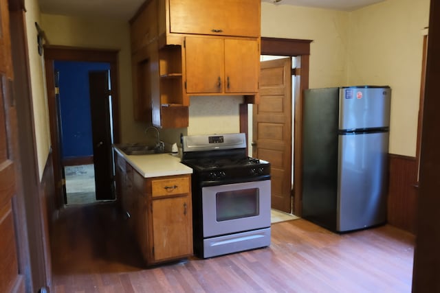 kitchen with light wood-type flooring, range with gas cooktop, sink, and stainless steel refrigerator