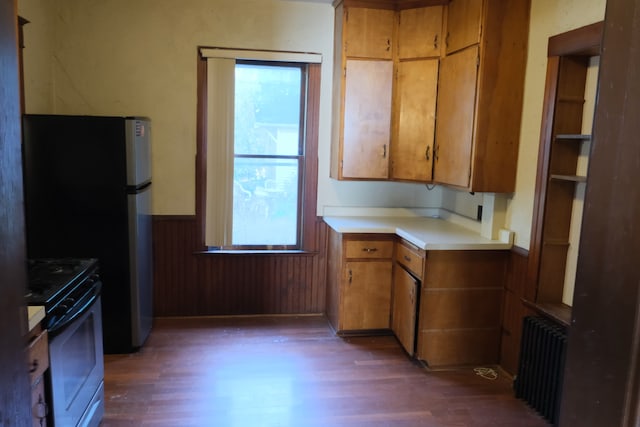 kitchen with dark wood-type flooring, range, stainless steel refrigerator, and radiator