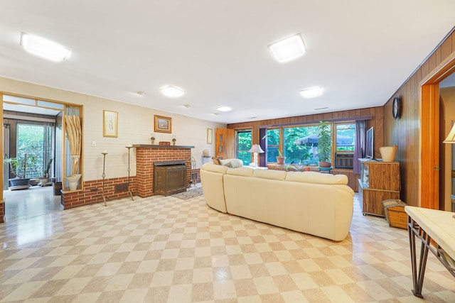 living room with wooden walls, a healthy amount of sunlight, and a brick fireplace