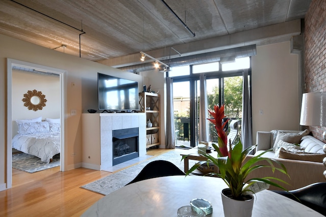 living room featuring light wood-type flooring, a tiled fireplace, and brick wall